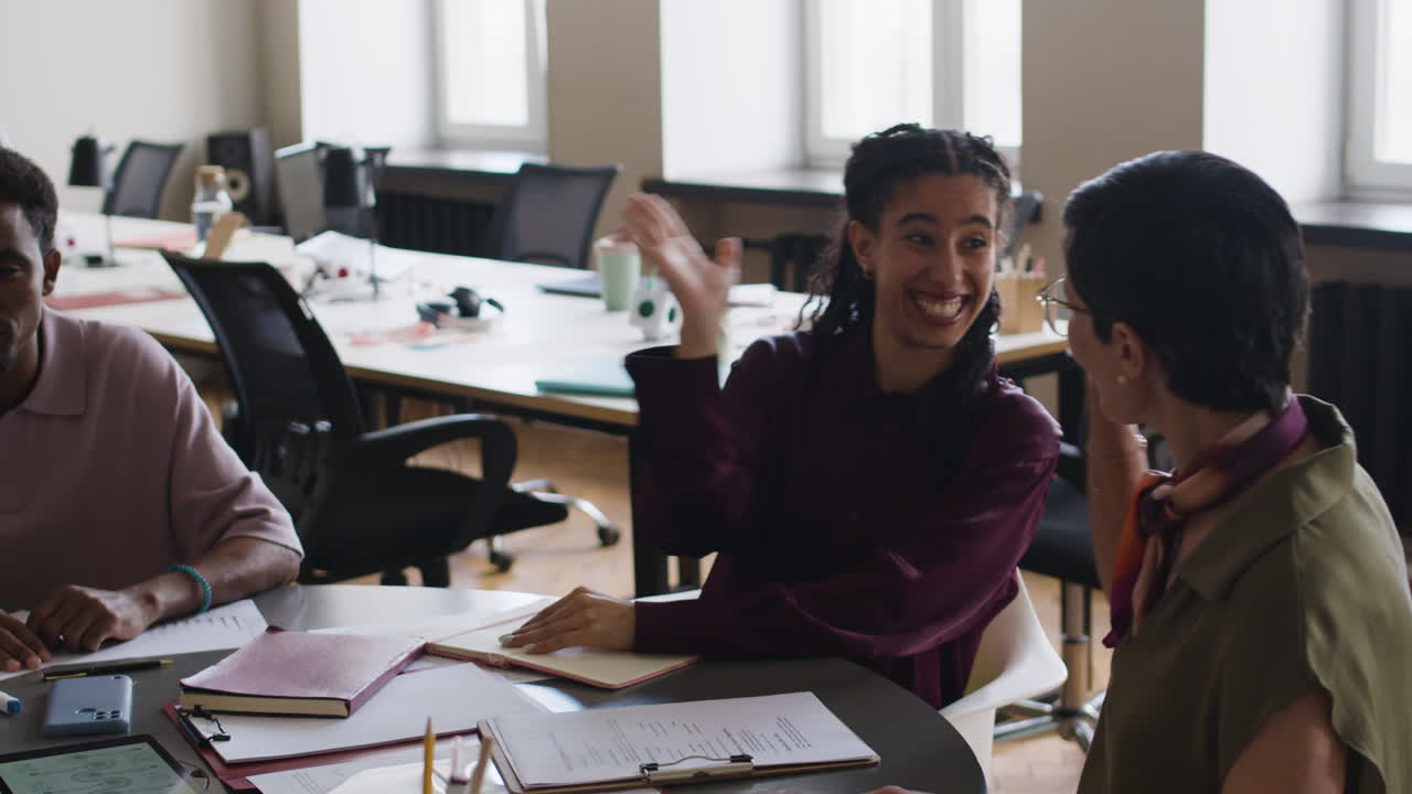 Diverse Team Celebrates Success with High-Fives at an Office Meeting