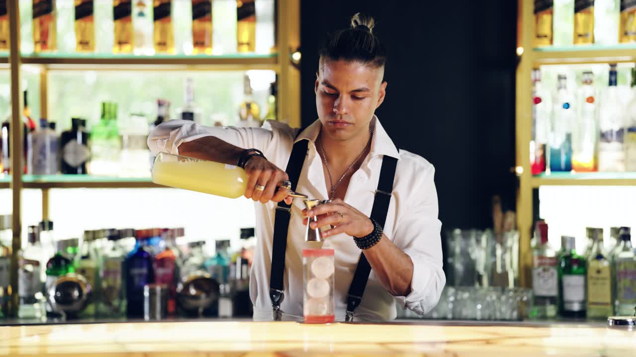 Professionele bartender schenkt ingrediënten voor een cocktail in aan een bar