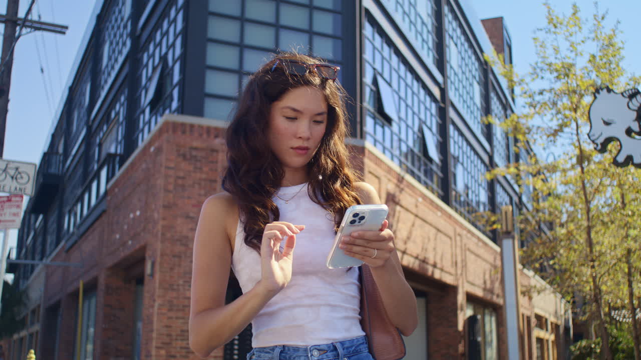 자신감 넘치는 갈색 머리카락의 스크롤 전화 클로즈업. 현대 스마트폰을 사용하는 아시아 여성.