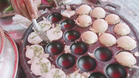 cocina de primer plano comida tradicional tailandesa de calle postre dulce khanom krok, panqueque de leche de coco mezcla azúcar y harina en proceso con cebollas de primavera en la parte superior