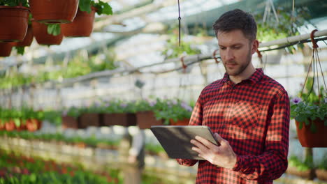 professional gardener using digital tablet in greenhouse