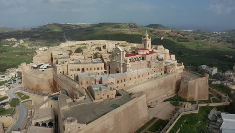 forward drone aerial shot of citadella a historical medieval fortress found on the beautiful island of gozo, malta in 4k quality with green hills surrounding it