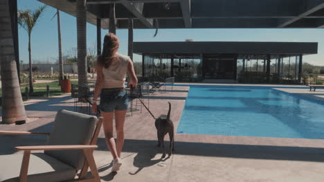 mujer joven paseando a su perro al aire libre en la zona de la piscina, cámara lenta