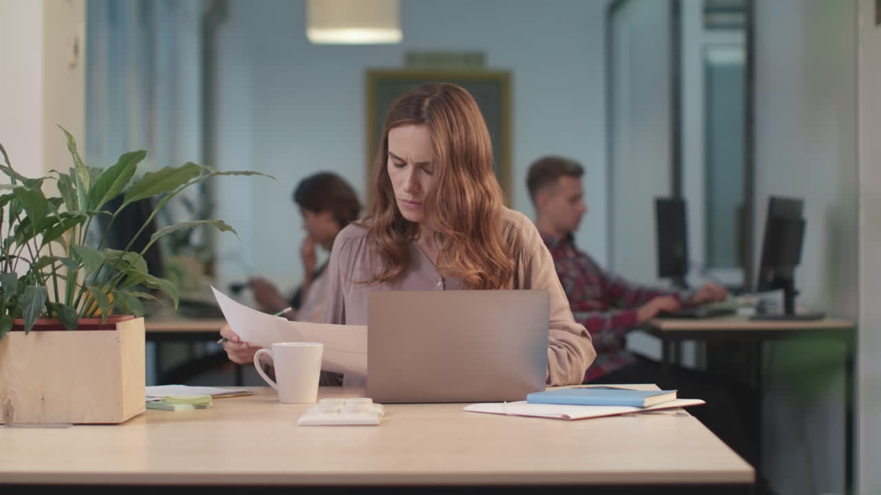 Donna d'affari che controlla i documenti. Lavoratrice concentrata che esamina le carte.