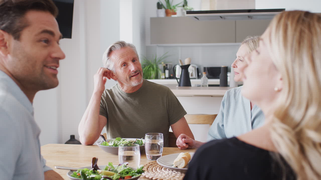 семья с пожилыми родителями и взрослым потомством ест еду за столом дома вместе