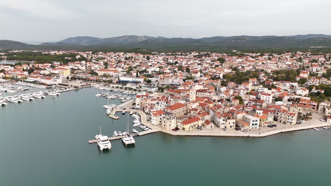 Ampio panorama aereo di Pirovac, che cattura la città, il lungomare e il porticciolo turistico in una tranquilla mattina autunnale lungo la costa adriatica