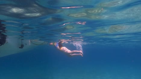 在水面下慢动作 漂浮在水面下靠近摩托船梯子的妇女场景