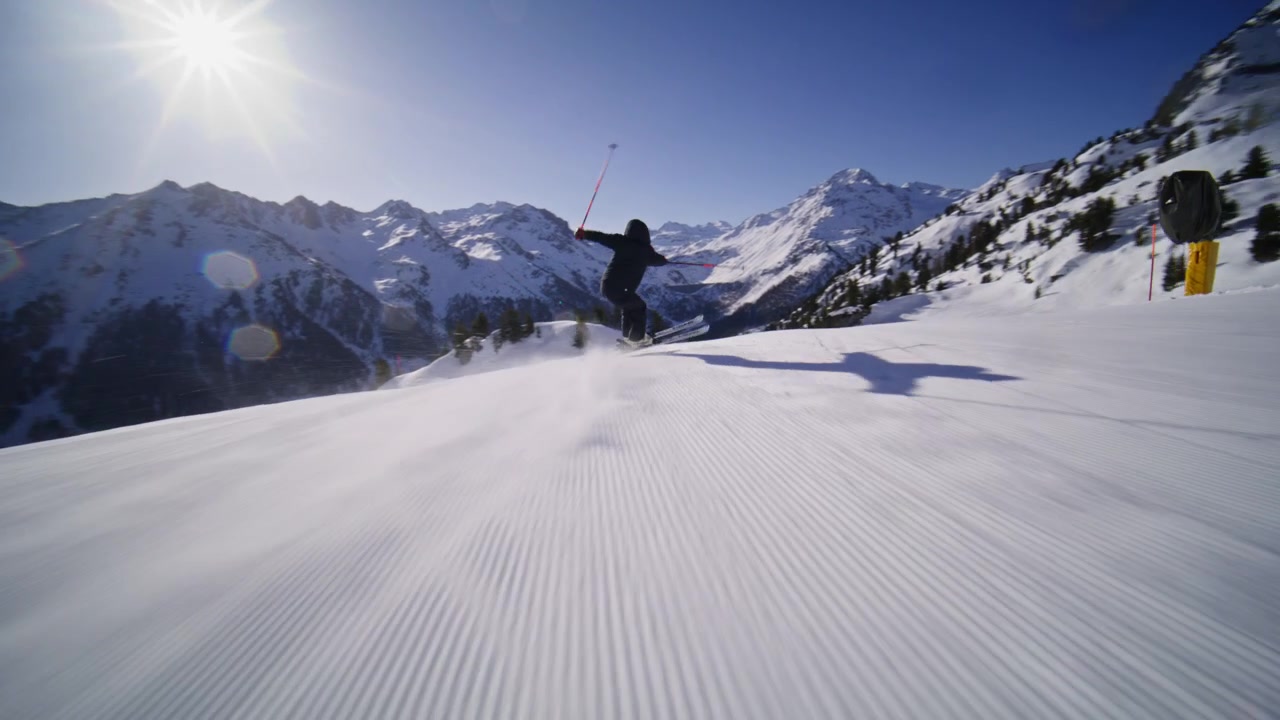 Sciatore che intaglia piste battute ad alta velocità a Nendaz, parte del comprensorio sciistico 4 Vallées nelle Alpi svizzere. Sci alpino d'élite con potenti spruzzi di neve e tecnica di precisione.