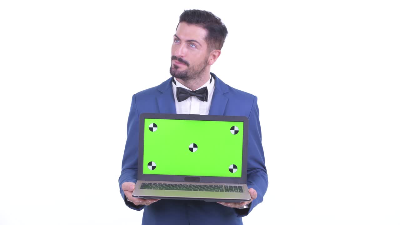 Portrait of businessman smiling and thinking while showing laptop with copy space