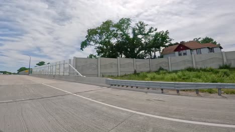 pov while driving on a portion of interstate 74 highway that is run through the quad cities in illinois with sound barrier walls to reduce noise in residential areas