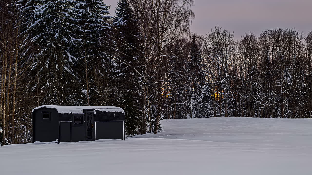 겨울 풍경에 눈 덮힌 써모우드 캐빈과 잎이 없는 나무, 일몰 시간경과