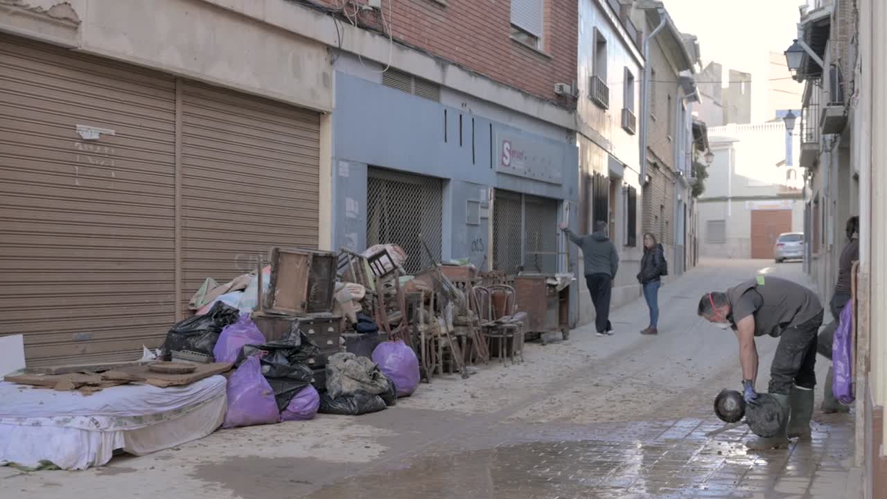 A person in protective gear clears debris and mud from a street after severe flooding. Effects of the DANA in Chiva, Valencia