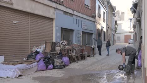 a person in protective gear clears debris and mud from a street after severe flooding. effects of the dana in chiva, valencia