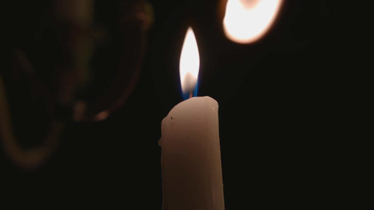 Una candela bianca solitaria accesa da un'altra candela