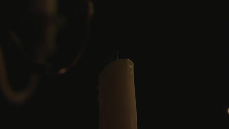 a lone white candle being lite by another candle