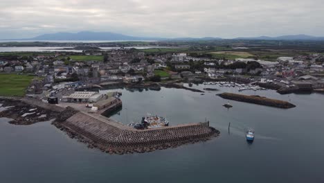 Vista-Aérea-De-Un-Barco-De-Pesca-Que-Sale-Del-Puerto-De-Ardglass-En-Un-Día-Nublado,-Condado-De-Down,-Irlanda-Del-Norte