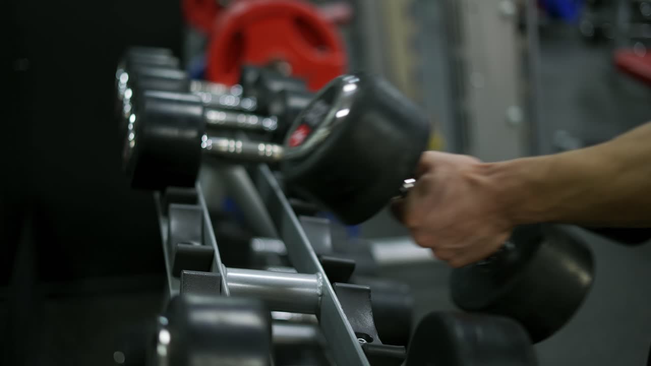 남자 손은 체육관 스탠드에서 덤벨을 잡습니다. 스포츠와 활동적인 생활 방식의 개념