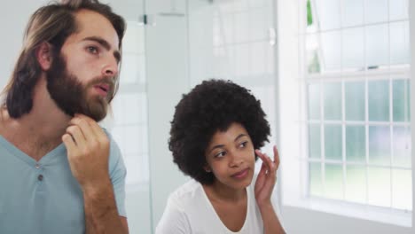 pareja de raza mixta mirándose en el espejo en el baño en casa