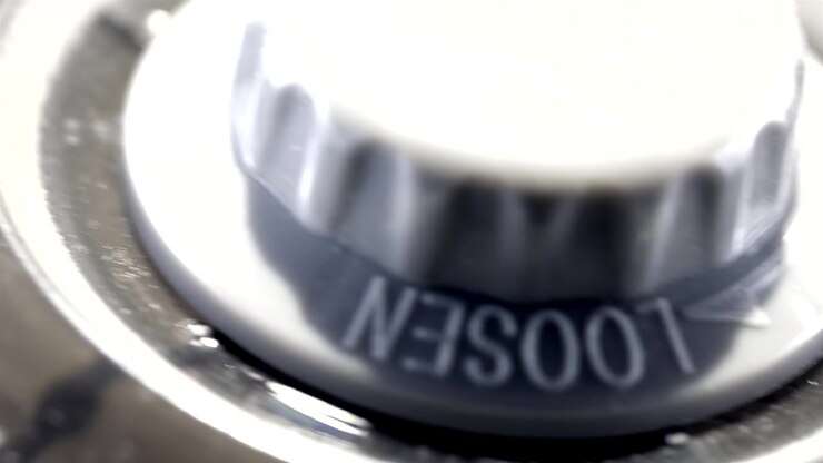 Dusty gray fan blade turns beside black grille bars in extreme close up.