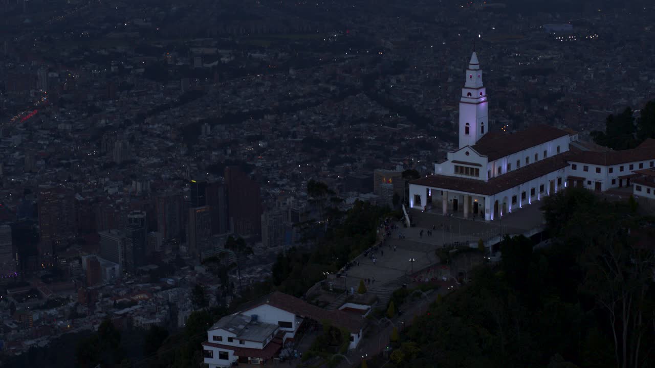 tomada de avión no tripulado de la iglesia de monserrate con vistas a la ciudad de bogotá, colombia en la hora azul