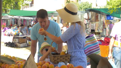 young family in market of thessaloniki greece choose peaches