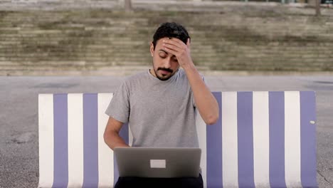 hombre cansado usando computadora portátil en la calle