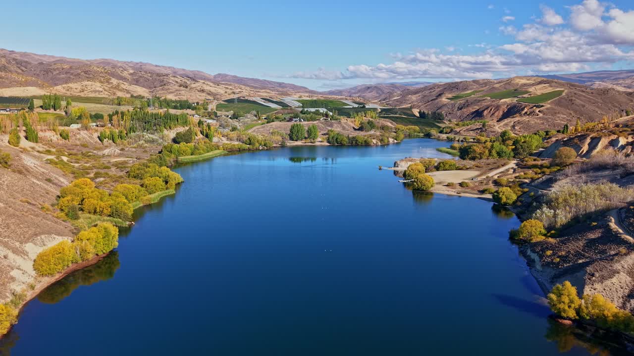 Kawarau River winds through scenic New Zealand landscape under blue sky