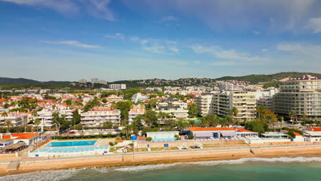 Drone-footage-captures-scenic-vistas-of-coastal-homes-by-beach,-offering-breathtaking-views-of-vast-sea-on-a-sunny-day