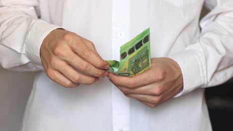 vídeo en cámara lenta. primer plano de las manos de un joven con una camisa blanca contando billetes de cien euros.