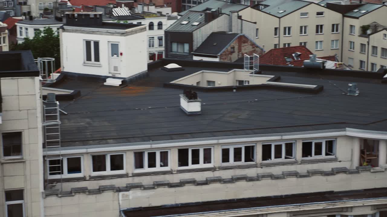 A smooth panning shot of city rooftops showcasing residential windows, chimneys, and detailed facades
