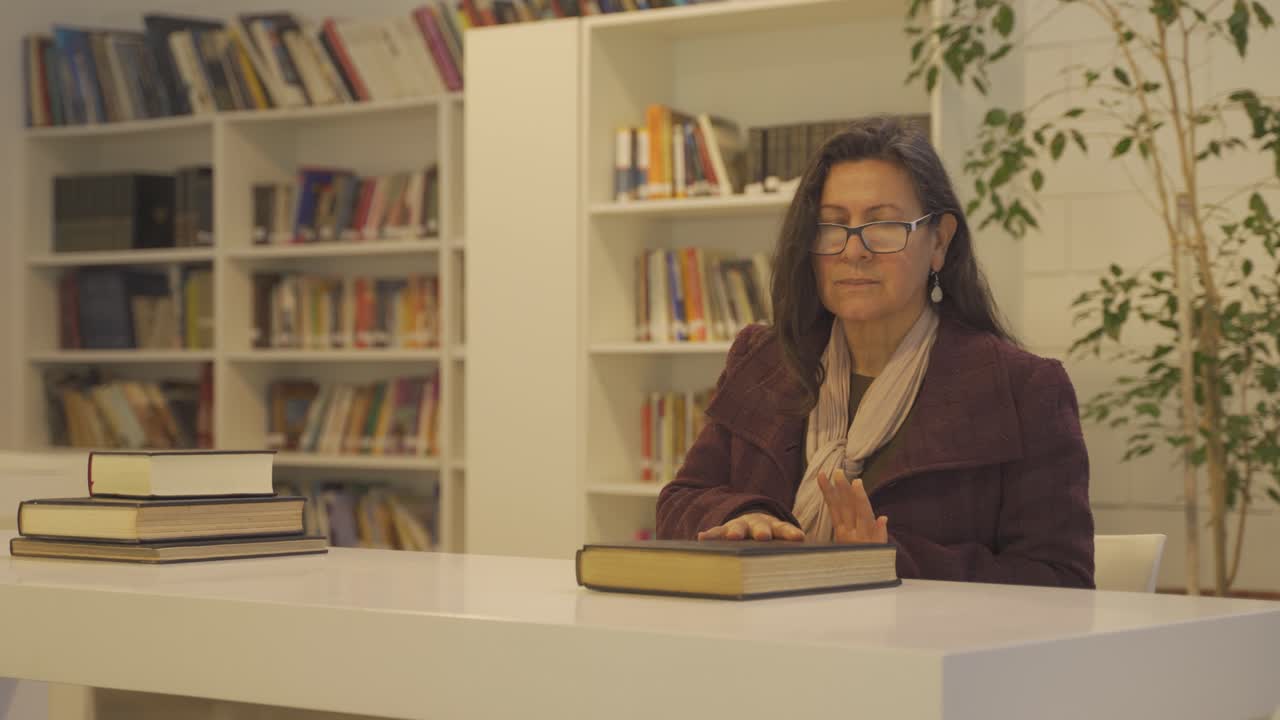 mujer concentrada cierra un libro después de terminar de leer y mirar a la cámara