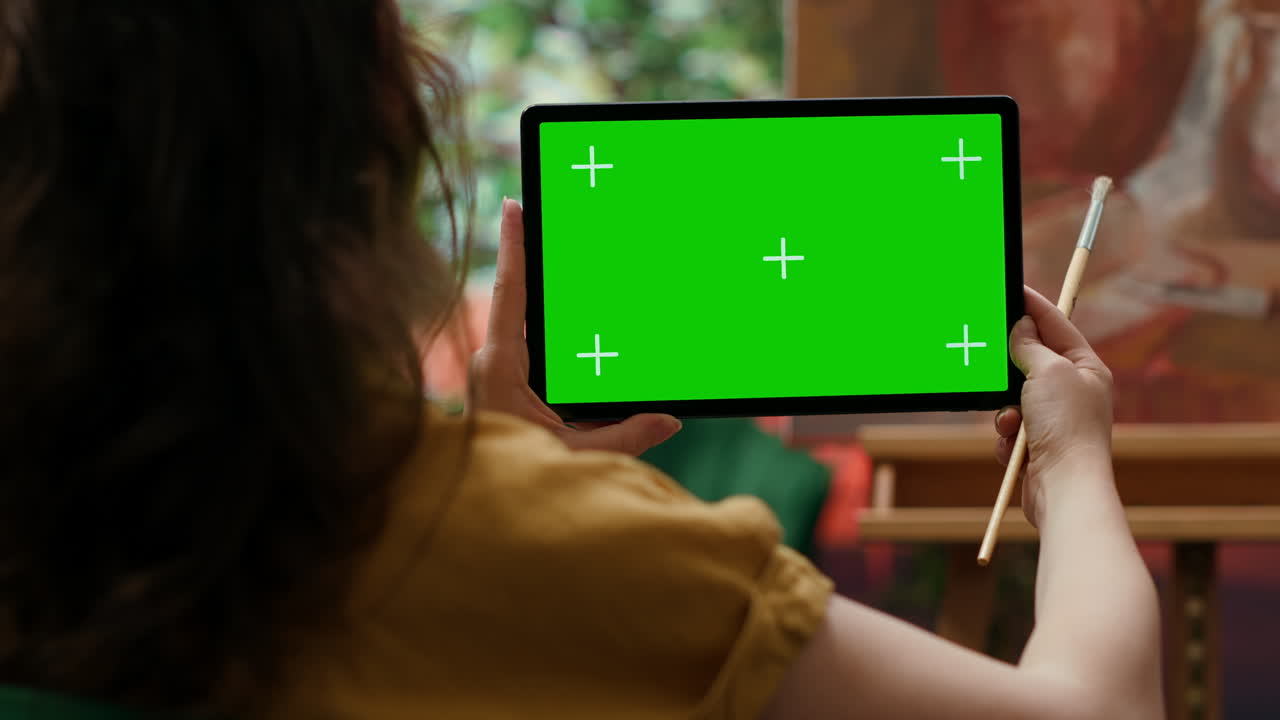 초록색 화면 을 가진 태블릿 을 들고 있는 여자