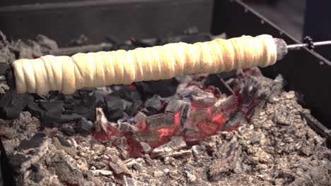 chimney cake dough turning on grill gridiron above glowing embers