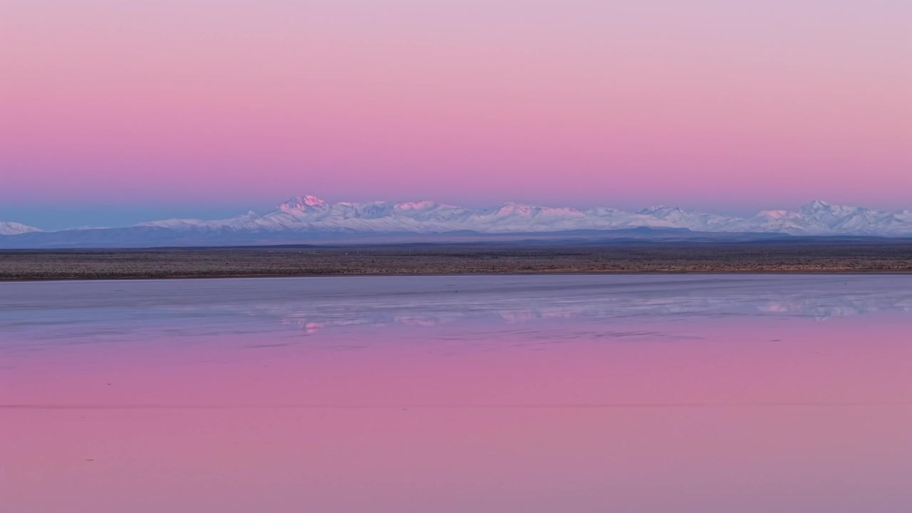 Riflessi di saline e cime innevate di Mendoza durante un colorato tramonto invernale. Ripresa aerea con tracciamento a destra.