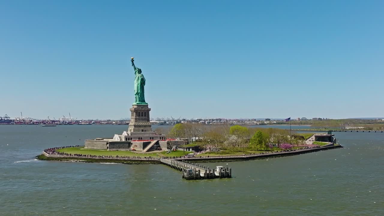 Aerial orbit shot: Statue of Liberty during sunny day with blue sky in NYC, America