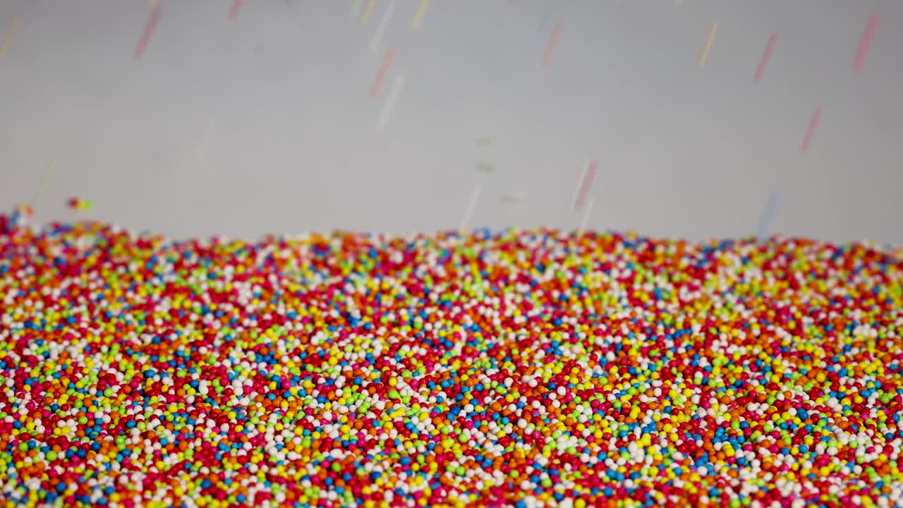 Vibrant sprinkles cascade against a neutral background, creating a dynamic and colorful visual effect