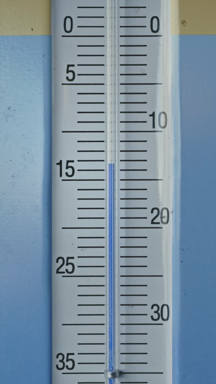 Vertical zoom in closeup of glass thermometer showing minus 15 celsius degrees , freezing cold winter temperature concept