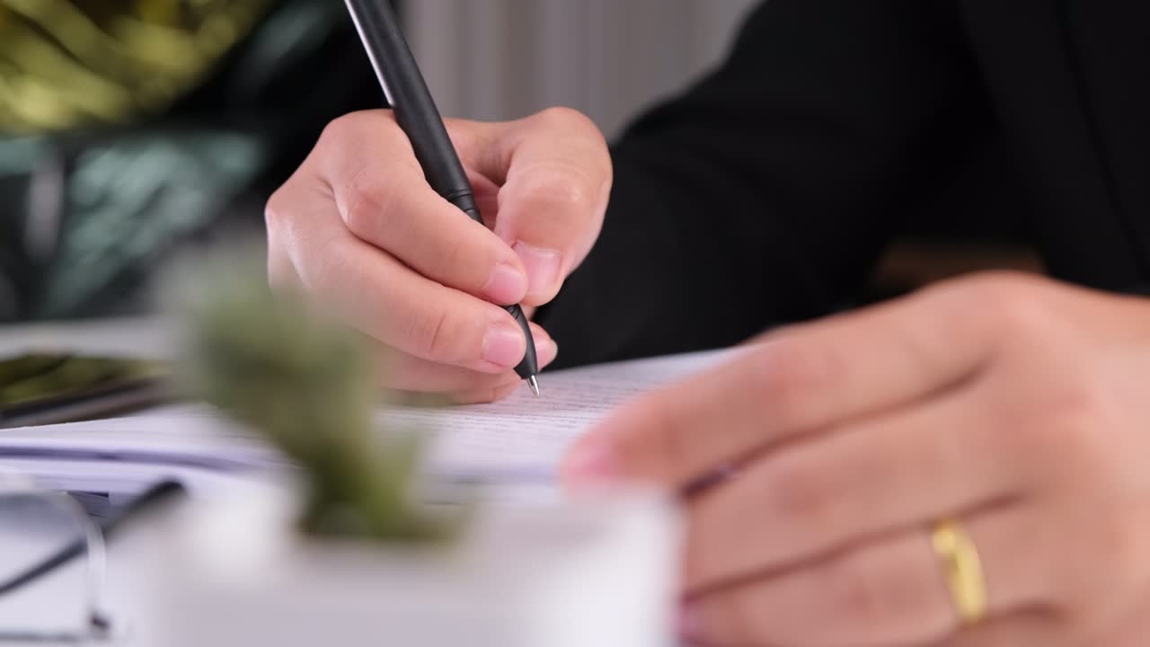 Primo piano delle mani di una donna d'affari che scrive un documento aziendale sul posto di lavoro