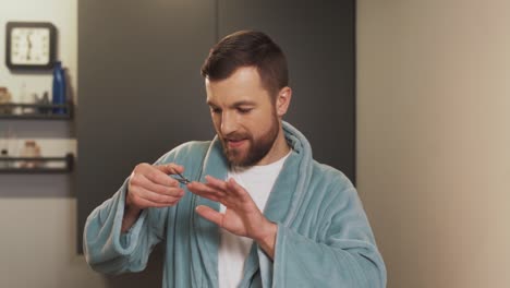 el hombre satisfecho está haciendo una manicura en el baño usando una bata de baño