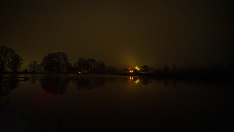 timelapse shot from night to morning over a lake in the foreground with a small wooden cottage in the background along rural countryside