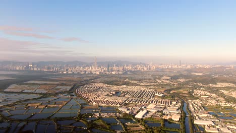 hong kong and shenzhen border line over hong kong rural houses with shenhzen skyline in the horizon, aerial view