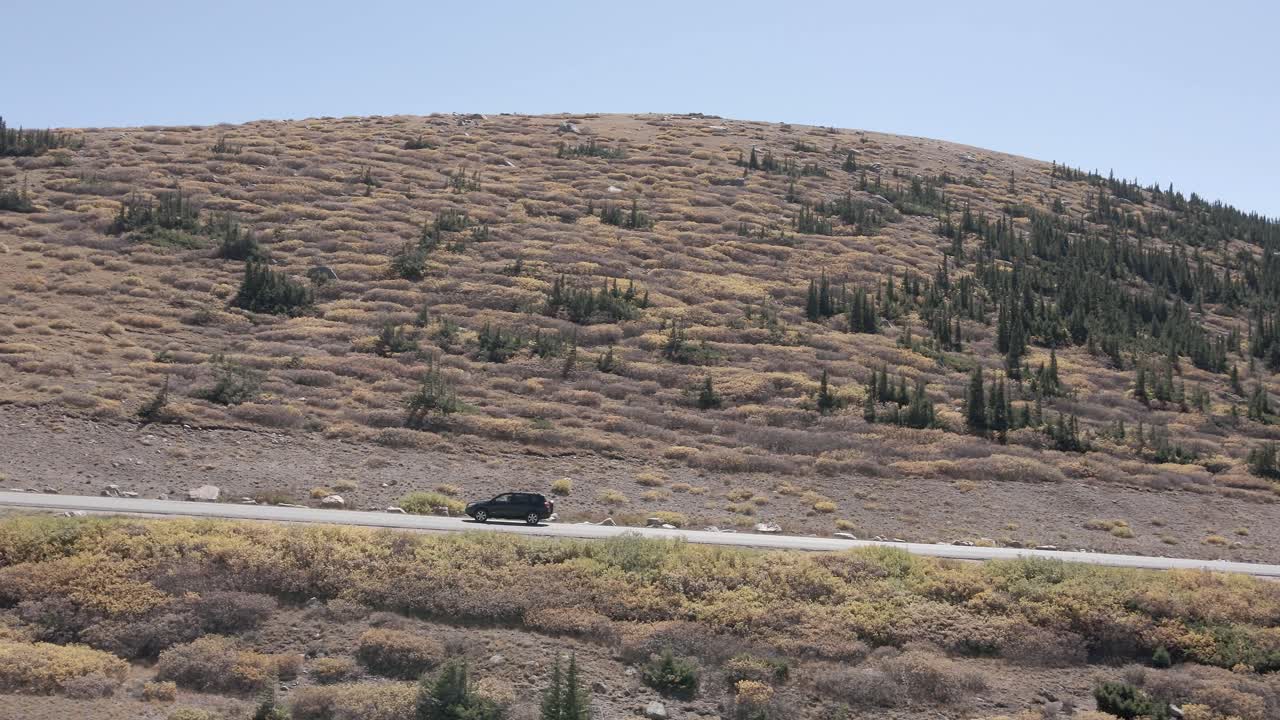 Aerial view of the Guanella Pass highway and a snow covered Mount Bierstadt while following a vehicle during the fall in Colorado. Filmed in the Rocky Mountains with a left trucking movement.