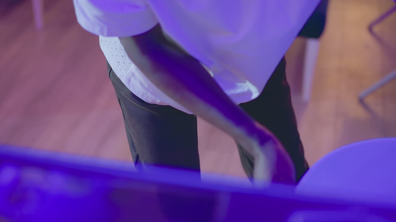 Close-up of bartender's hand adjusting equipment on bar counter with purple lighting. Scene captures focus on detailed bar setup in a modern, professional lounge environment
