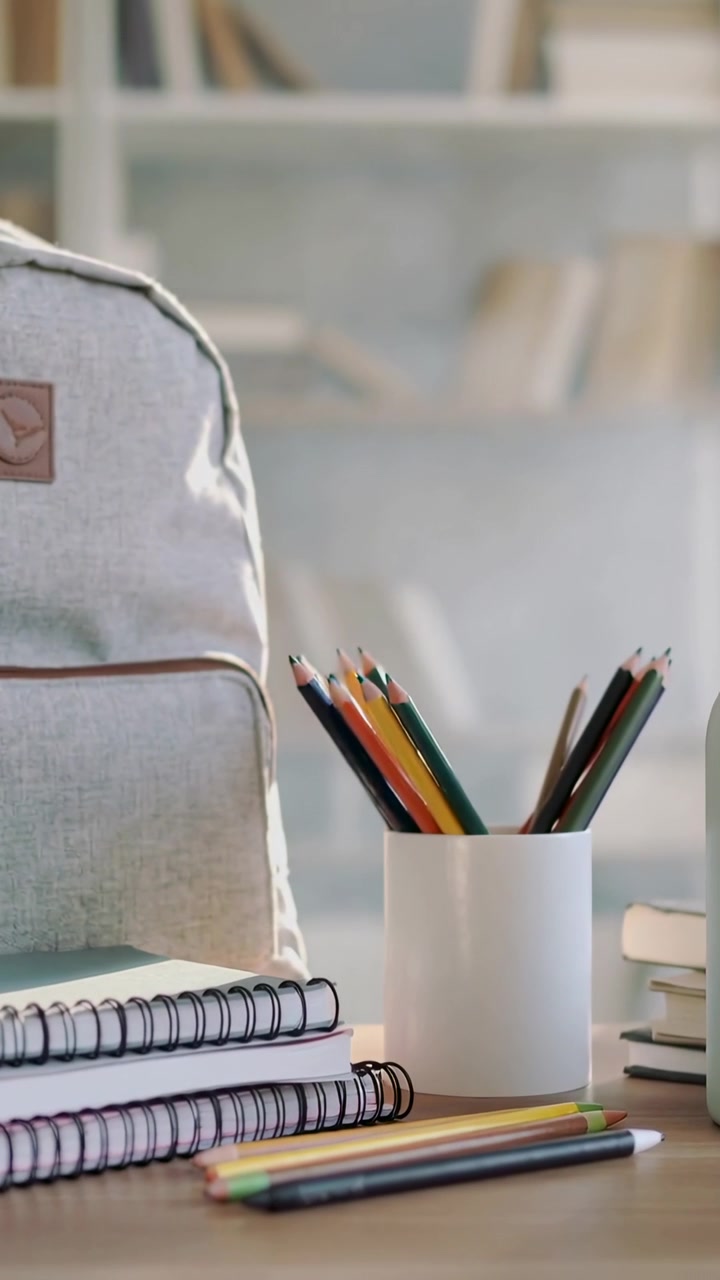 Vertical video: Shifting camera moving over home desk, bringing pencil cup and notebooks closer