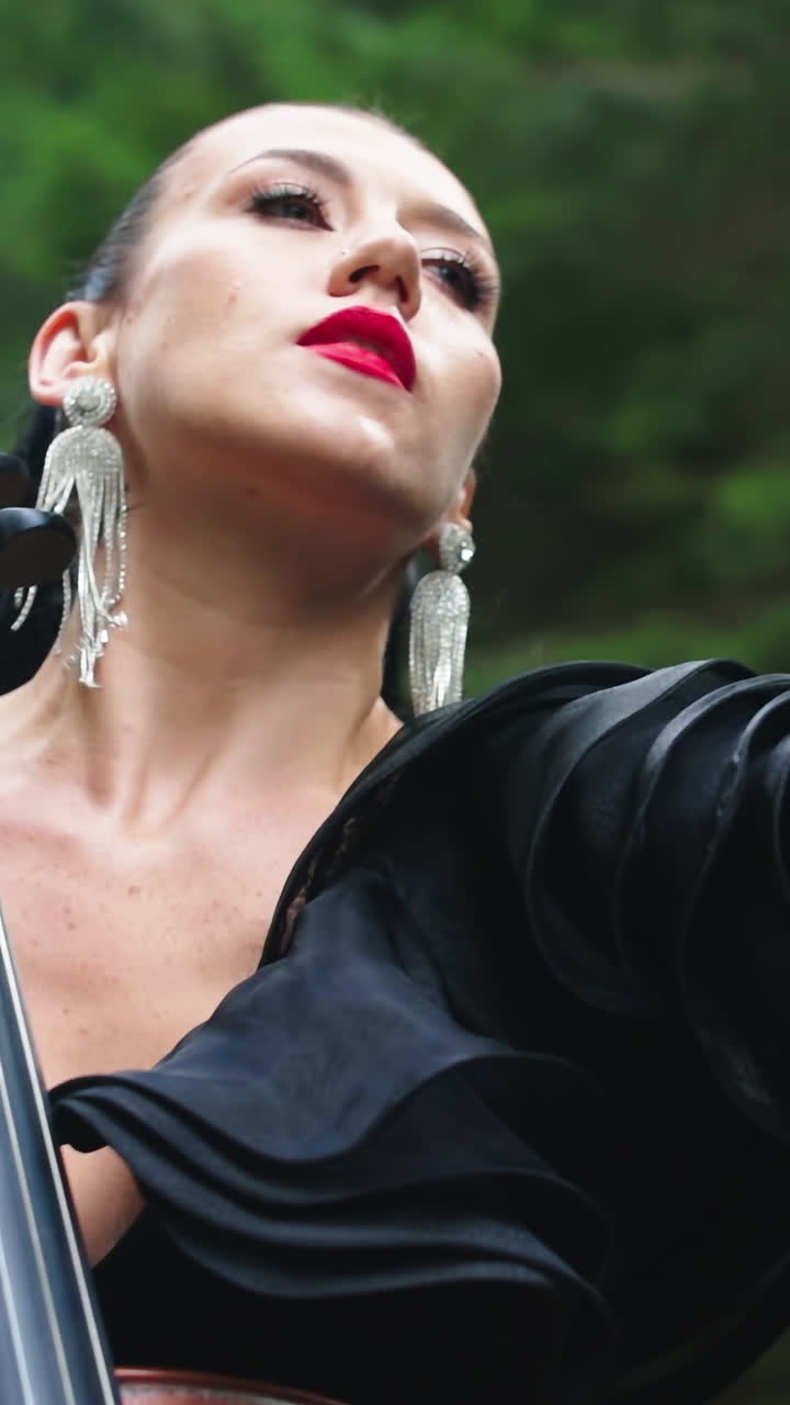 Girl playing cello outdoor. Beautiful young woman playing cello outdoors