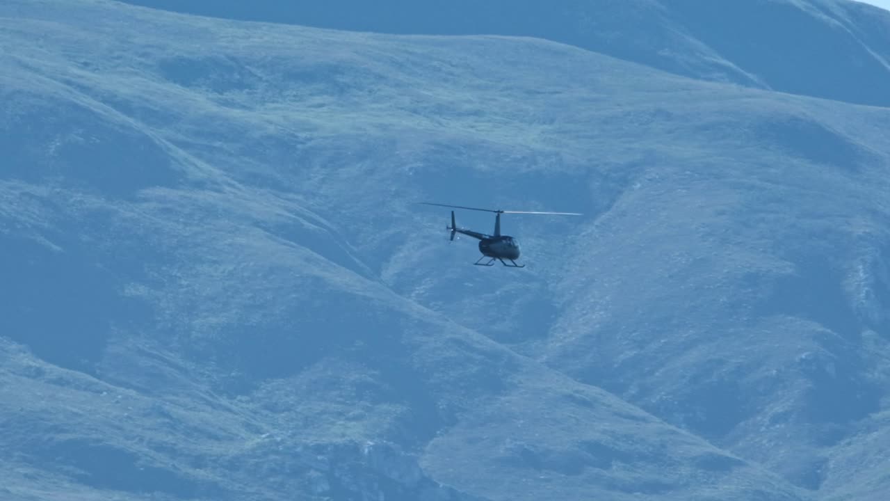 A chopper flying and operating in a mountainous terrain