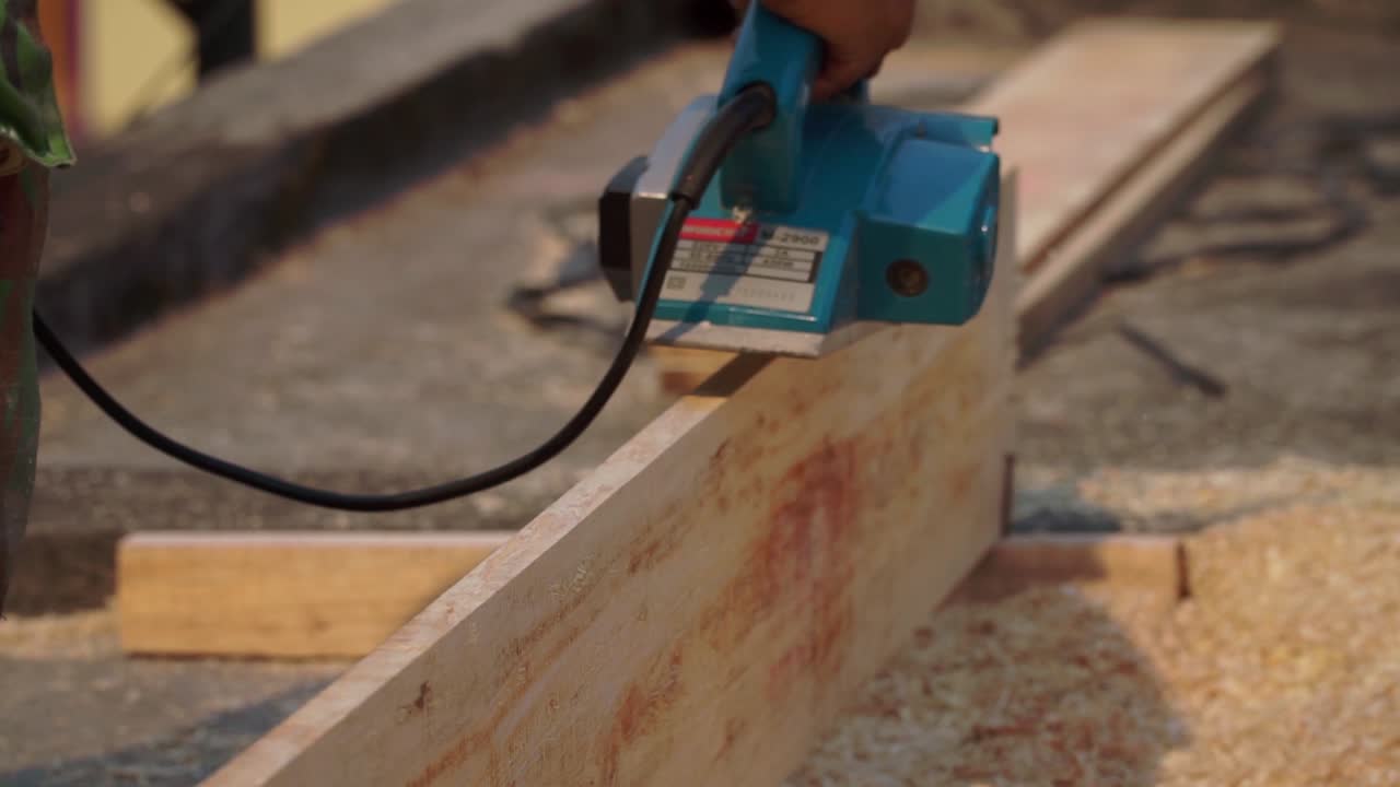 Carpenter hand work using planer machine to smooth the surface of plank wood