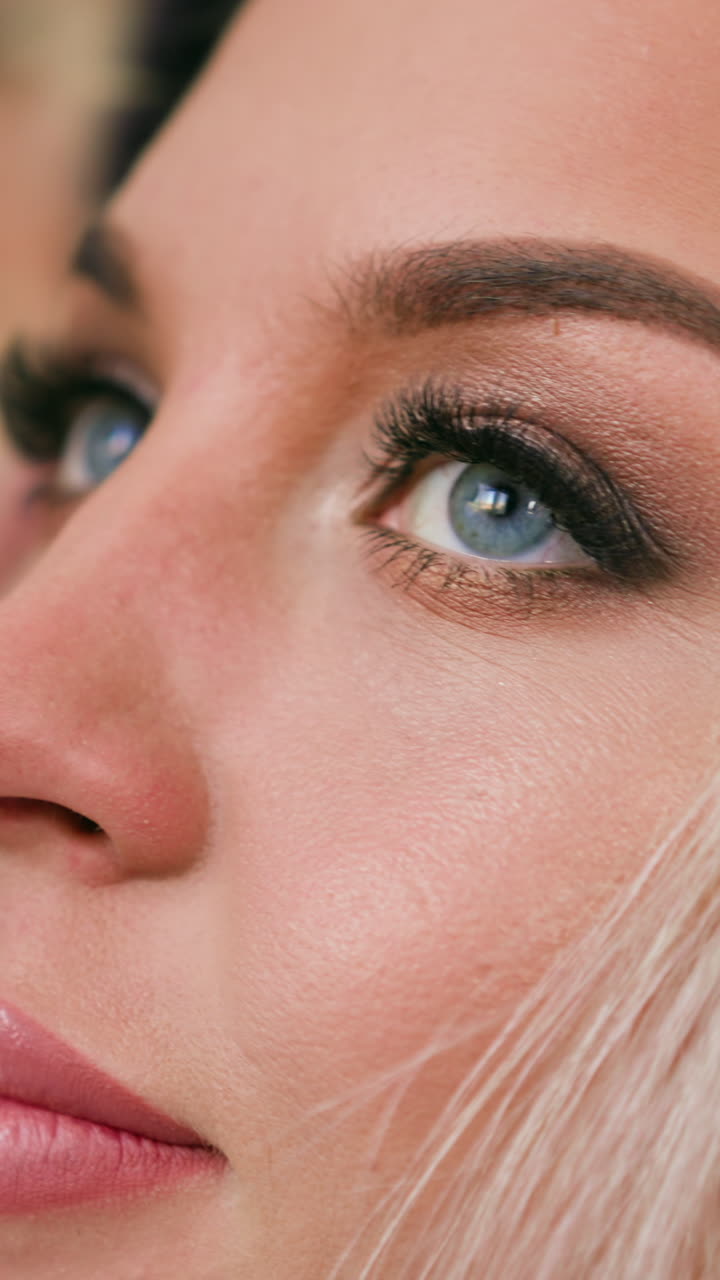 Attractive positive woman with elegant makeup talks to hairstylist preparing for festive event in modern beauty salon closeup slow motion