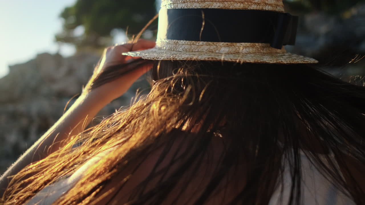 mujer con un sombrero de paja disfrutando de la puesta de sol junto al mar