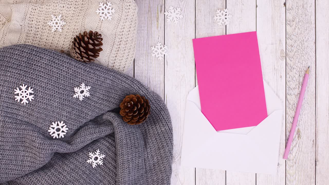Decorazione invernale con maglioni lavorati a maglia, ornamenti, pigne e carta in busta per auguri. Stop motion